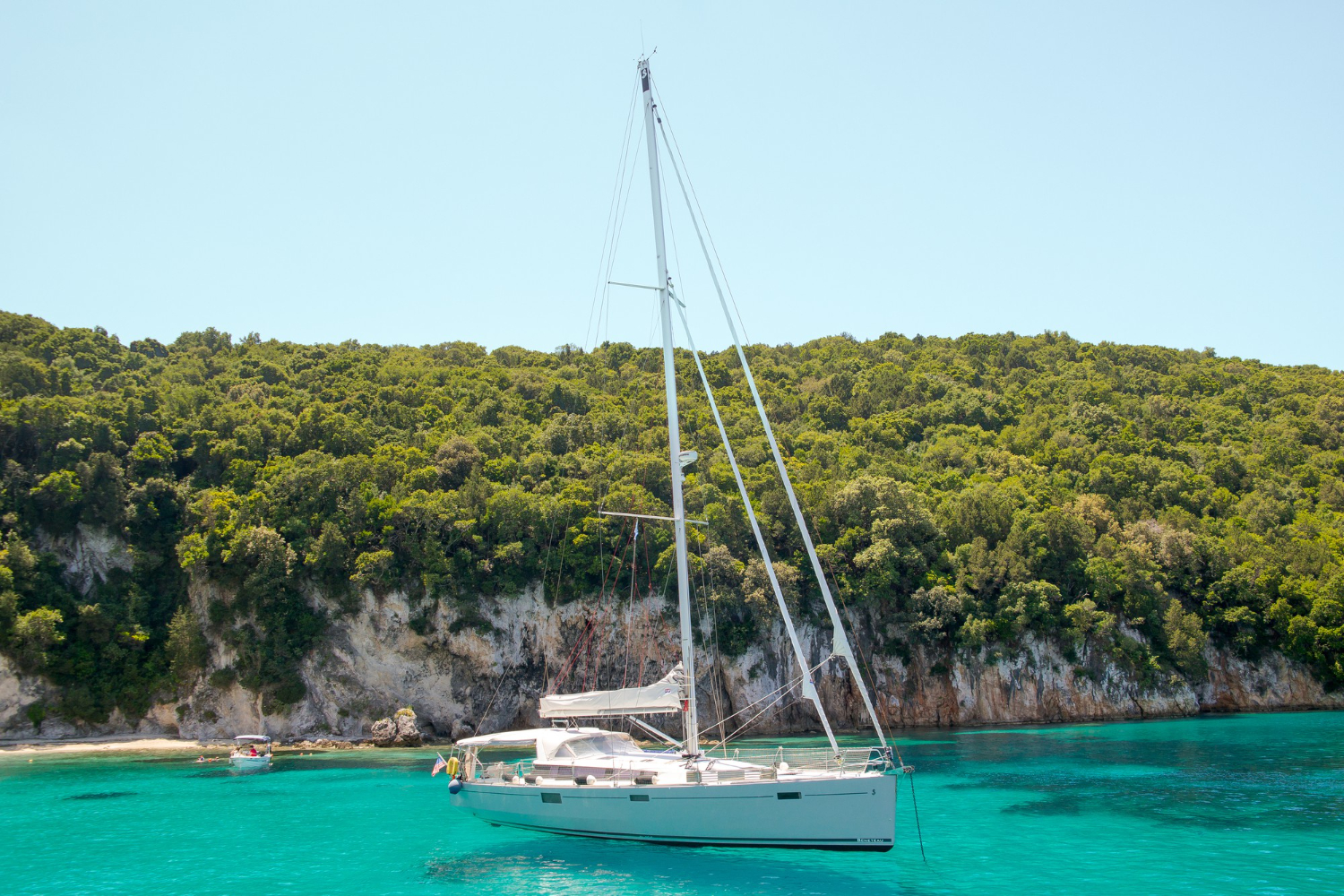 Luxury yacht anchored near a sandy beach with clear blue waters